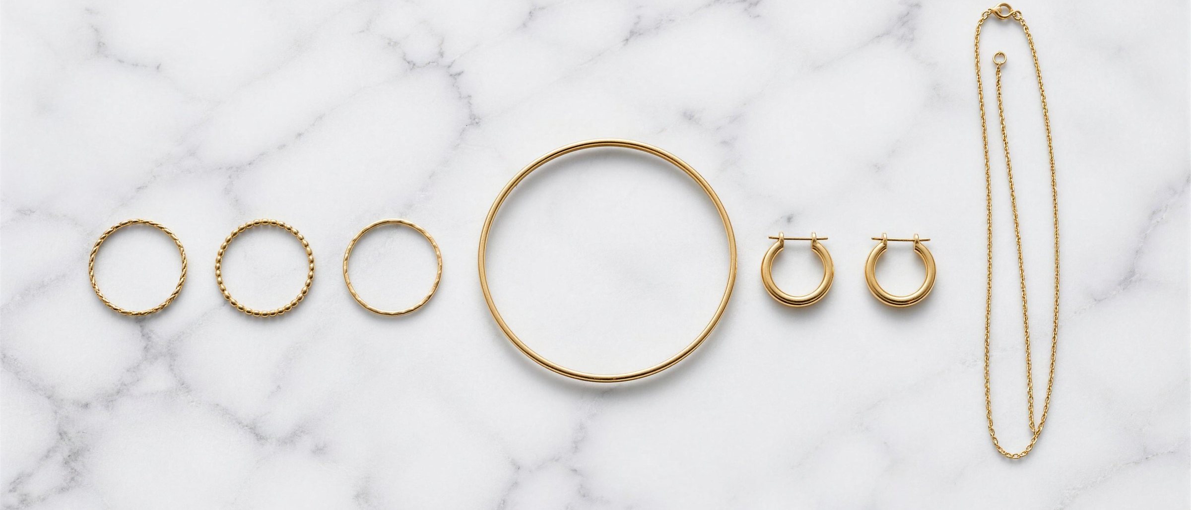 Overhead flat lay of fine gold jewellery on marble
